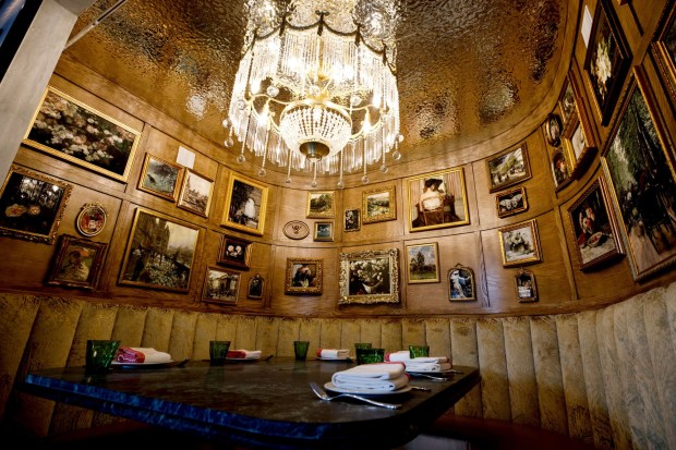 A chandelier-lit booth featuring surrounding art at À L'ouest in North Park. (Kristian Carreon / The San Diego Union-Tribune)