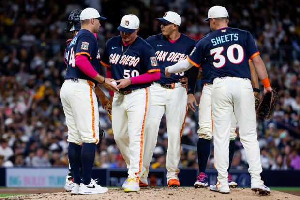 Adrian Morejon #50 of the gives the ball to Craig Stammen of the San Diego Padres during the eighth inning against the Colorado Rockies at Petco Park on Friday, April 10, 2026 in San Diego, California. (Meg McLaughlin / The San Diego Union-Tribune)