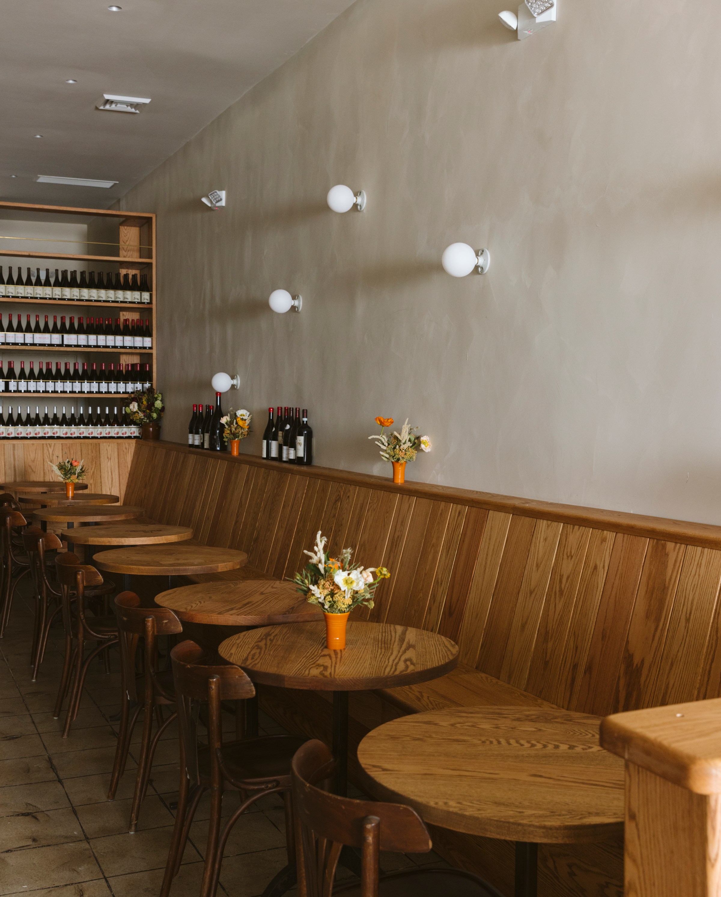 A wooden banquette row under midcentury-style sconcers.