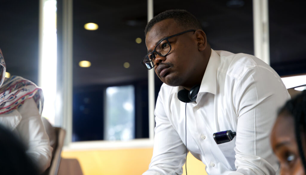 A seated man listens intently to a presentation