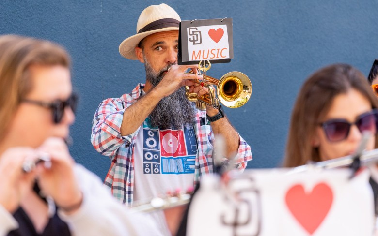A musician plays his trumpet as a raucous crowd turns out to oppose city budget cuts. (Photo by Thomas Murphy/Times of San Diego)