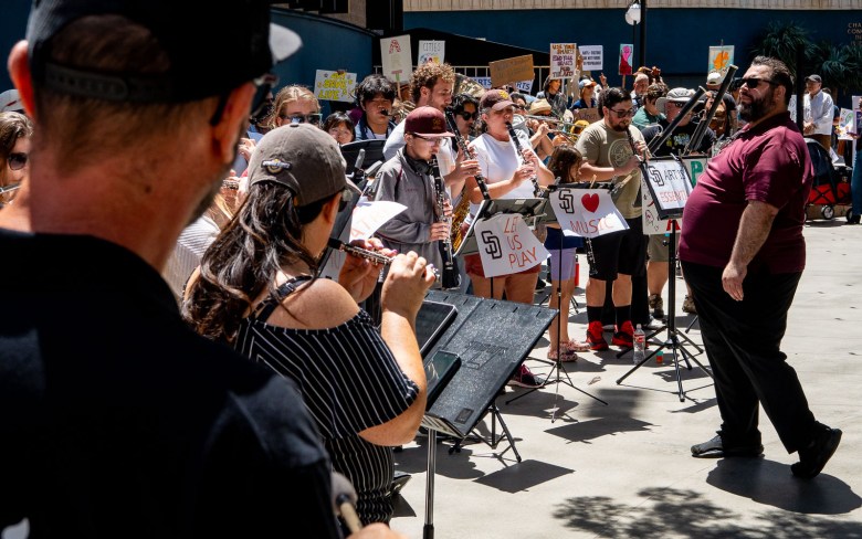 An orchestra shows up to play amid a crowd of San Diegans who turned out on April 20, 2026 to oppose city budget cuts affecting the arts. (Photo by Thomas Murphy/Times of San Diego)