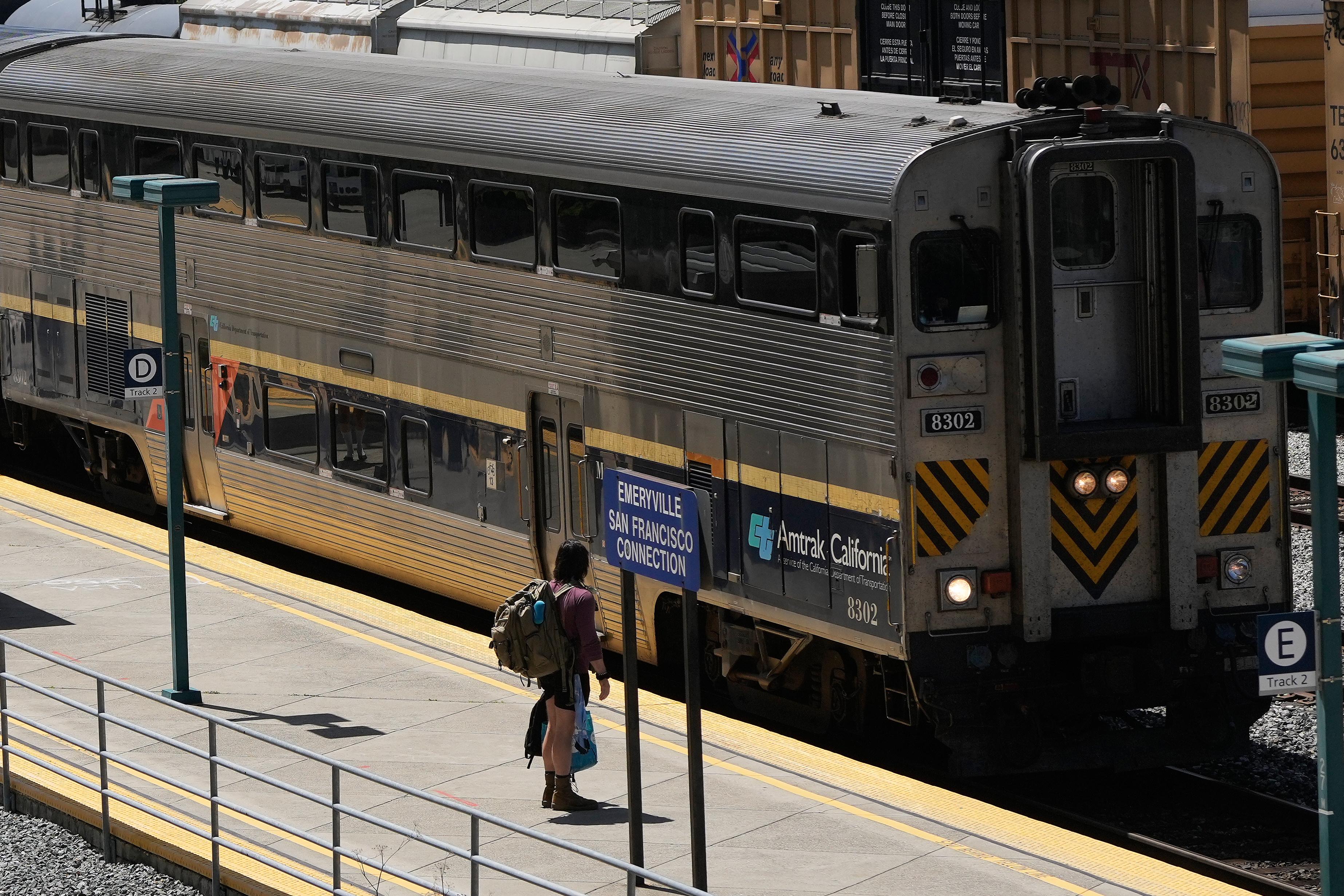 A passenger waits to board an Amtrak train at a...