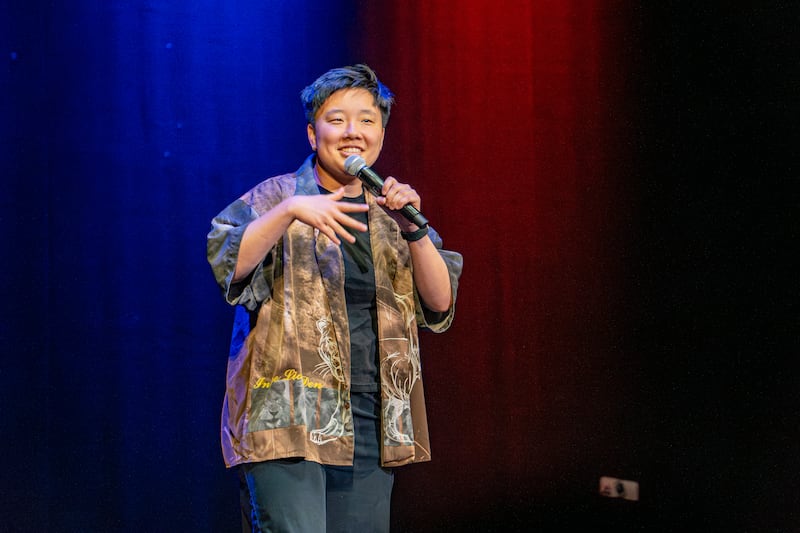 Sabrina Wu stands in front of a black backdrop in the blue light.