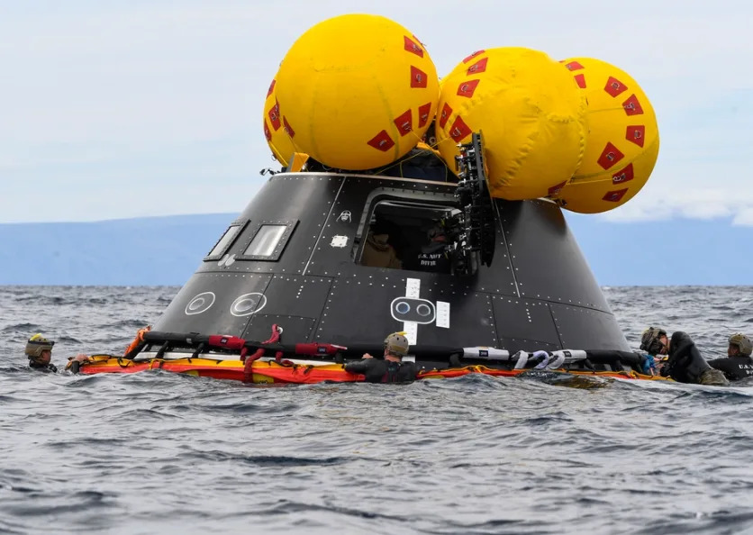 U.S. Navy Divers assigned to Explosive Ordnance Disposal Mobile Unit 1 fasten a NASA “front porch” life raft to a crew module test article (CMTA) during Underway Recovery Test 11, Feb. 25, 2024. In preparation for NASA’s Artemis II crewed mission, which will send four astronauts in Orion beyond the Moon, NASA and the Department of Defense will conduct a series of tests to demonstrate and evaluate the processes, procedures and hardware used in recovery operations for crewed lunar missions. Amphibious transport docks, like USS San Diego, have unique capabilities that make it an ideal partner to support NASA, including embarking helicopters, launching and recovering small boats, three dimensional air search radar and advanced medical facilities. (U.S. Navy photo by Mass Communication Specialist 2nd Class Connor Burns)