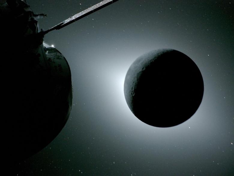 The Moon, seen here backlit by the Sun during a solar eclipse on April 6, 2026, is photographed by one of the cameras on the Orion spacecraft’s solar array wings. Orion is visible in the foreground on the left. Earth is reflecting sunlight at the left edge of the Moon, which is slightly brighter than the rest of the disk. The bright spot visible just below the Moon’s bottom right edge is Saturn. Beyond that, the bright spot at the right edge of the image is Mars.