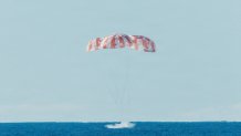 The Orion space craft splashes down in the ocean near the amphibious transport dock ship USS John P. Murtha (LPD 26) after returning from space on April 10, 2026. John P. Murtha is underway in the U.S. 3rd Fleet area of operations supporting NASA’s Artemis II mission, retrieving the crew and space craft following their return to Earth and splashdown in the Pacific Ocean. NASA’s Artemis II mission sent four astronauts on a flight around the moon in the Orion space craft, marking the first time humans jou