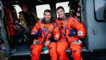 NASA astronaut Reid Wiseman, left, and Canadian Space Agency astronaut Jeremy Hansen pose for a photo in an U.S. Navy MH-60S Seahawk attached to Helicopter Sea Combat Squadron (HSC) 23 on the flight deck of the San Antonio Class amphibious transport dock USS John P. Murtha (LPD 26) after returning from space on Apr. 10, 2026. John P. Murtha is underway in the U.S. 3rd Fleet area of operations supporting NASA’s Artemis II mission, retrieving the crew and spacecraft following their return to Earth and splas