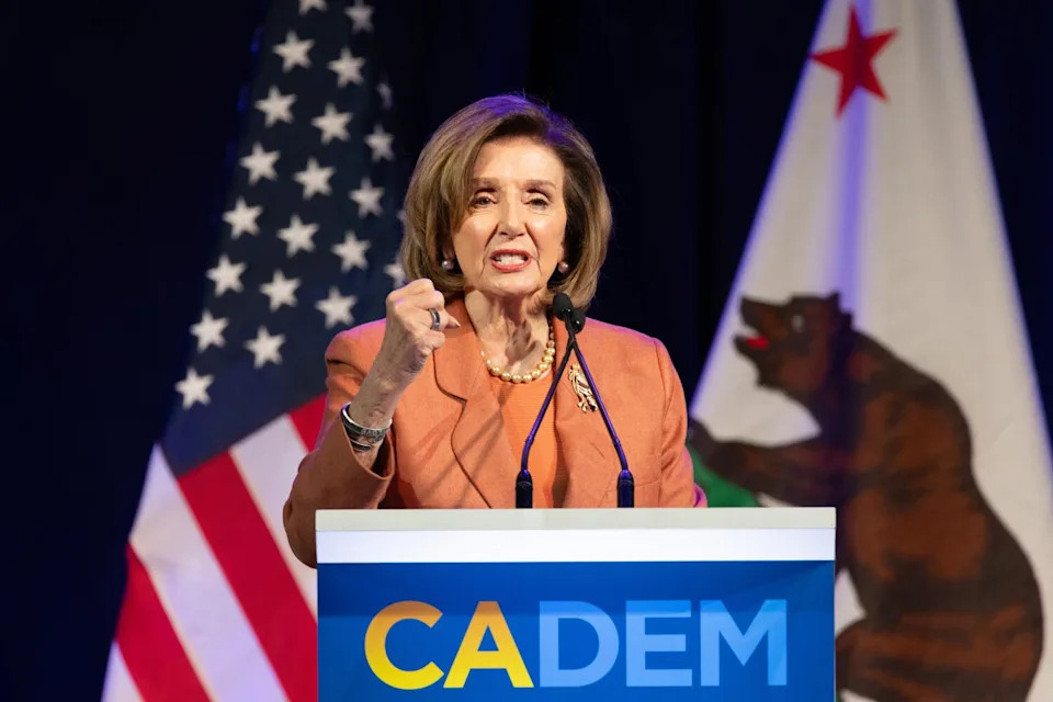 A woman speaks into microphones at a lectern.