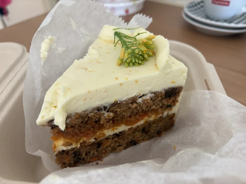 A slice of carrot take with orange marmalade filling in a take out container.