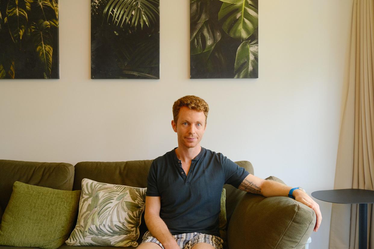 A man sitting on a green couch in Singapore.