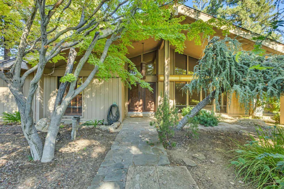 Boasting two primary suites, four bathrooms, and expansive living spaces on a 1.3-acre lot, the late mid-century modern home offers both vintage charm and modern functionality.