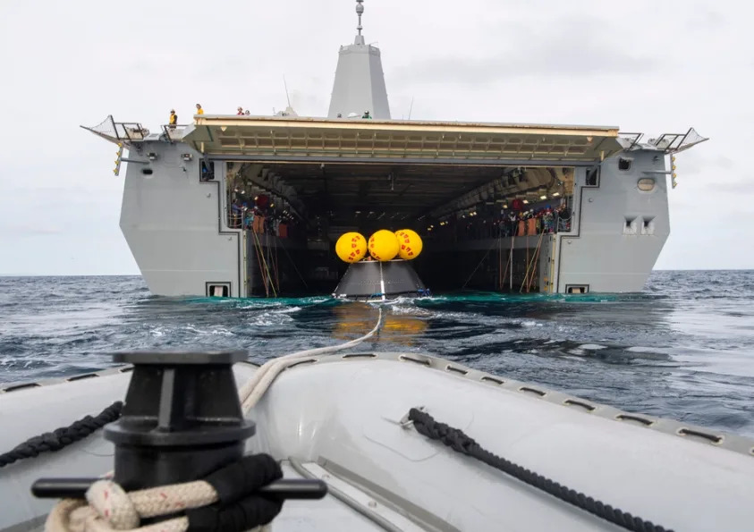 A rigid hull inflatable boat tows a crew module test article (CMTA) from the well deck of San Antonio-class amphibious transport dock ship USS San Diego (LPD 22) during Underway Recovery Test 11, Feb. 25, 2024. In preparation for NASA’s Artemis II crewed mission, which will send four astronauts in Orion beyond the Moon, NASA and the Department of Defense will conduct a series of tests to demonstrate and evaluate the processes, procedures and hardware used in recovery operations for crewed lunar missions. Amphibious transport docks, like USS San Diego, have unique capabilities that make it an ideal partner to support NASA, including embarking helicopters, launching and recovering small boats, three-dimensional air search radar and advanced medical facilities. (U.S. Navy photo by Mass Communication Specialist 2nd Class Connor Burns)