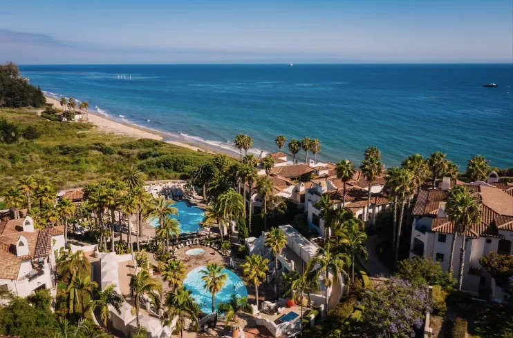 Aerial view of the Ritz-Carlton Bacara resort in Santa Barbara with pools, palm trees, and the Pacific Ocean coastline in the background