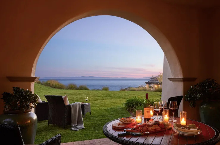 Ocean view from Terranea Resort in Palos Verdes with outdoor dining table, archway, and Pacific coastline at sunset