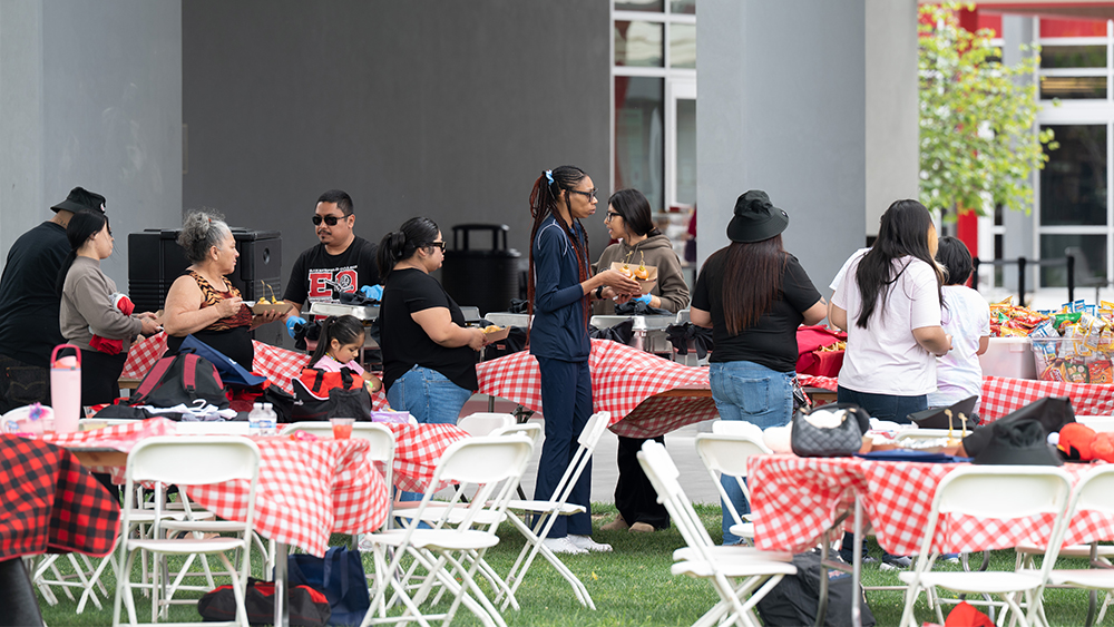 several people standing at a serving table getting good