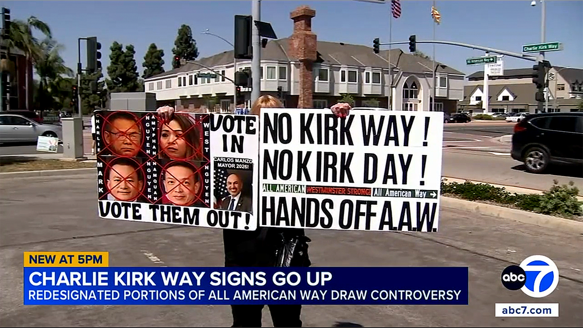 Protester in Westminster, CA holds up signs protesting a street being renamed after Charlie Kirk