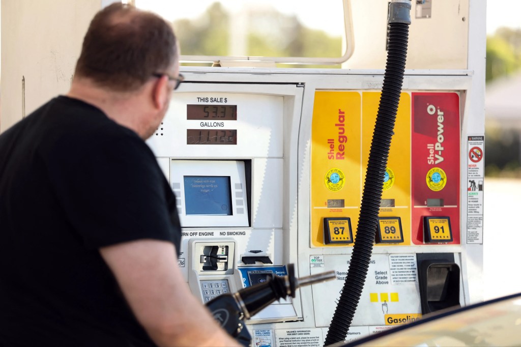 A man pumping gasoline into his vehicle at a gas station.