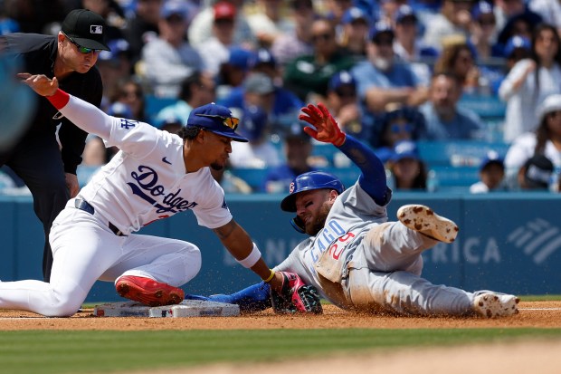 Chicago Cubs' Michael Busch (29) safely slides into third base as Los Angeles Dodgers third baseman Santiago Espinal, second from right, reaches to tag him during the second inning of a baseball game Sunday, April 26, 2026, in Los Angeles. (AP Photo/Caroline Brehman)