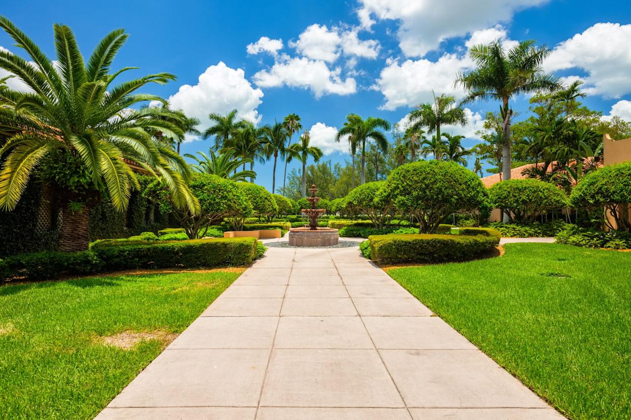 A landscaped hotel garden with palm trees, a central fountain, and quiet walking paths offers a relaxing stay near Disneyland
