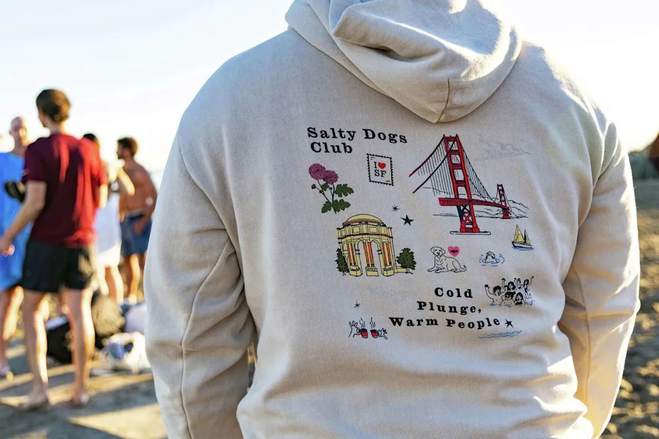 A member of the Salty Dogs Club San Francisco wears the group's sweatshirt on the beach before its Friday morning plunge off Crissy Field. (Jana Ašenbrennerová/For the S.F. Chronicle)