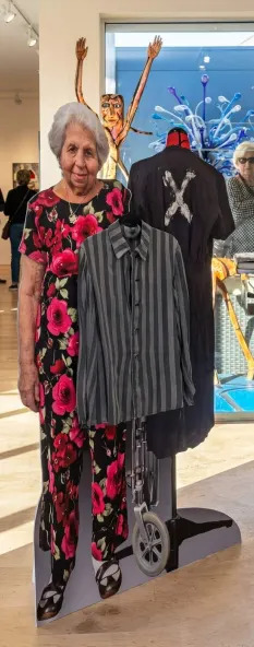 An image of Holocaust survivor Ruth Saks stands beside an original concentration camp uniform, a centerpiece of the recent RUTH fundraising event. (Courtesy of RUTH: Remember Us The Holocaust initiative)