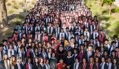large number of students in grad regalia standing on a large staircase