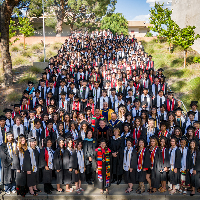 large number of students in grad regalia standing on a large staircase