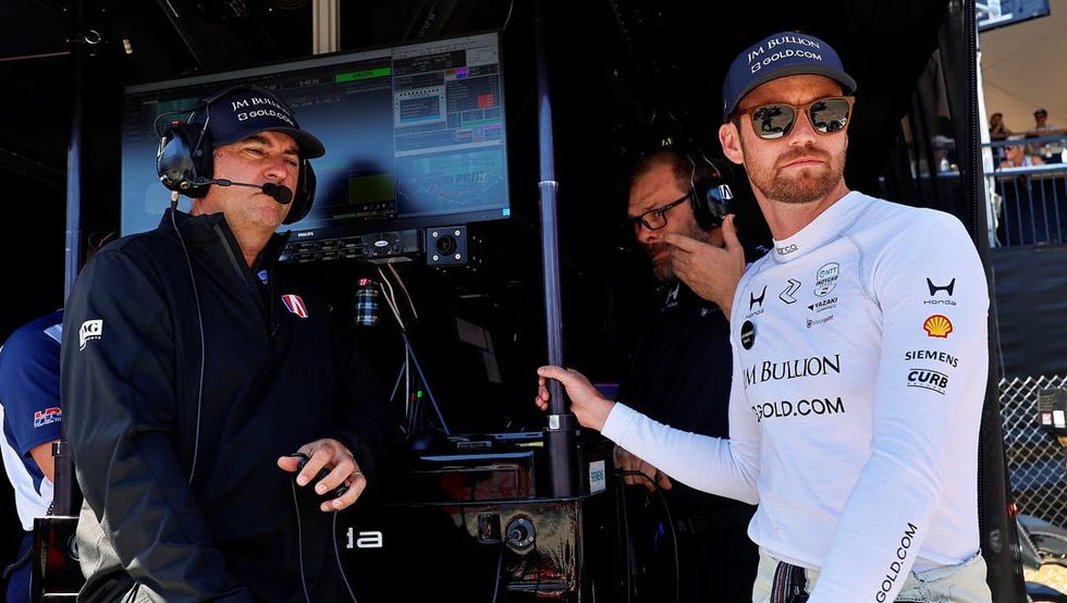 team members discussing strategy near a digital screen during a race