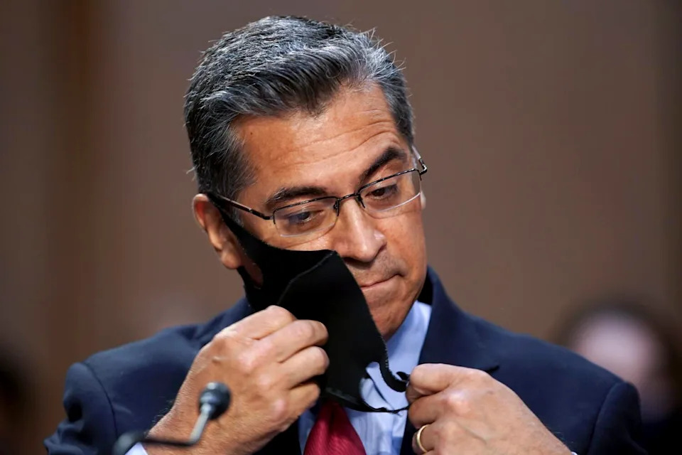 Xavier Becerra removes a face mask during a hearing