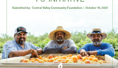 three men standing at a fruit bin