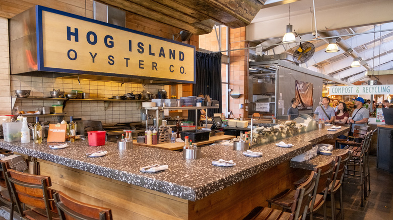 The oyster bar and at Hog Island Oyster Co. with oysters on ice, stools, and a kitchen in San Francisco.