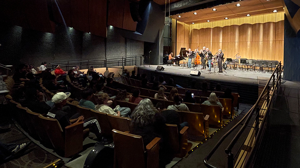 wide shot of performing jazz group on stage and the audience listening