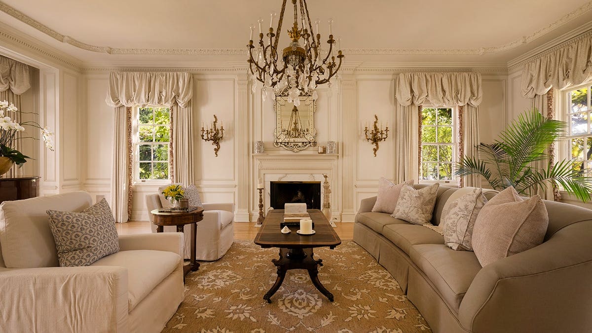 A living room with two sofas, a chandelier and a fireplace.
