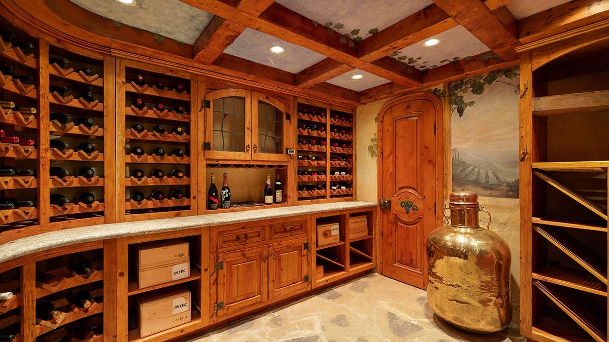 A wine cellar with square beams on the ceiling and painted walls.