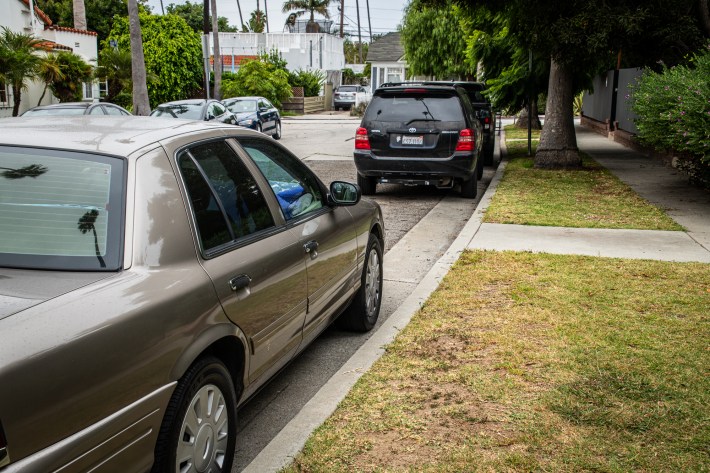 a view of a street with cars lined up, parked