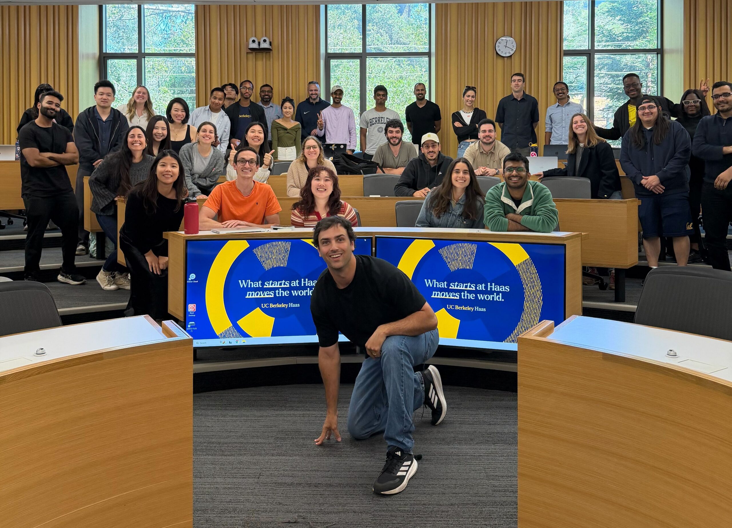 man kneeling in front of a class of students
