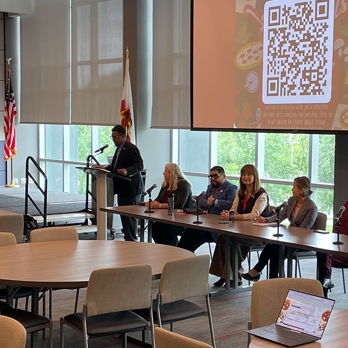 panelists talking to attendees while sitting at a long table