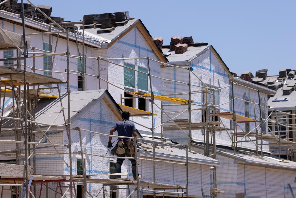 Construction of single-family homes with scaffolding and a worker on a scaffold.