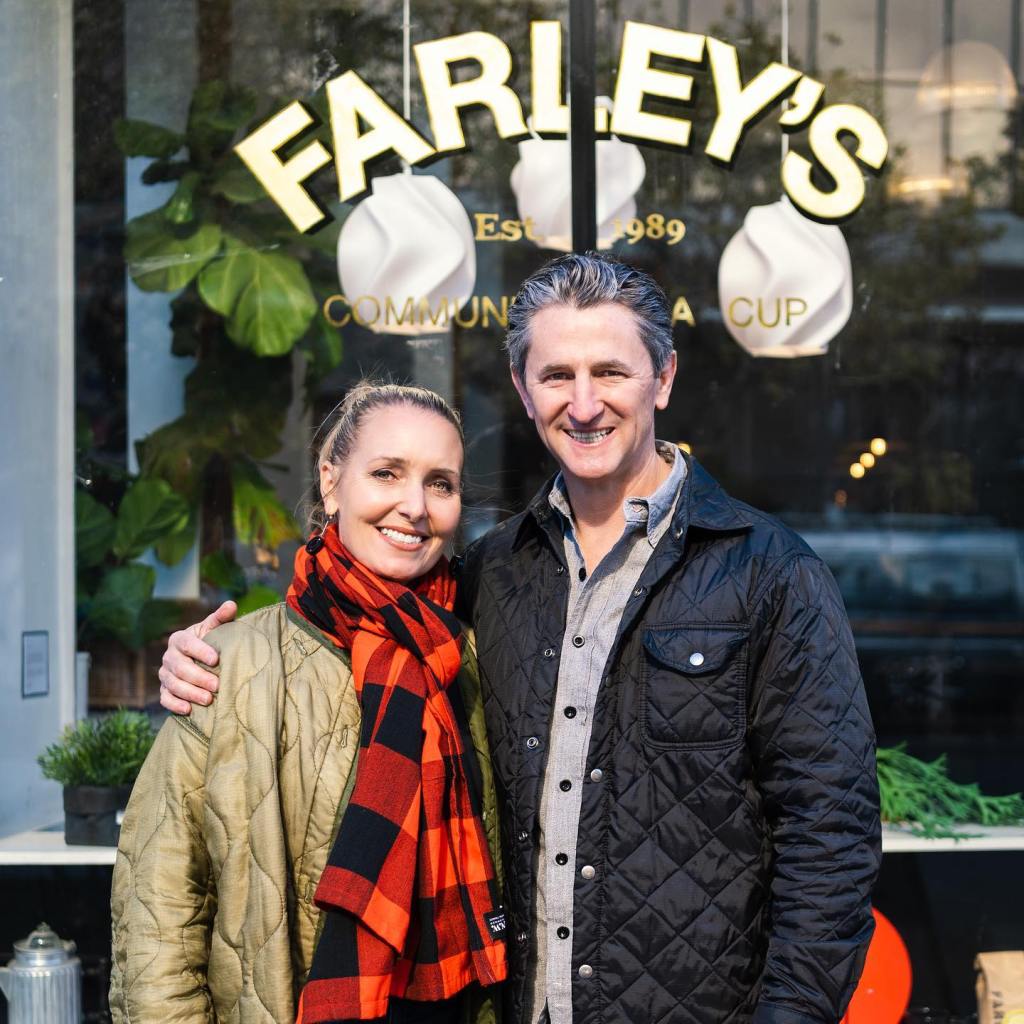 Amy Hilyard stands with her arm around a man, both smiling in front of a store window.