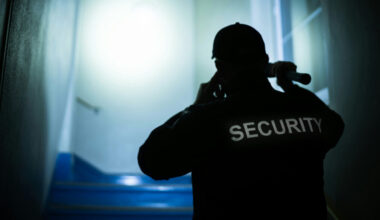 A security guard, seen from behind in silhoutte, with the word