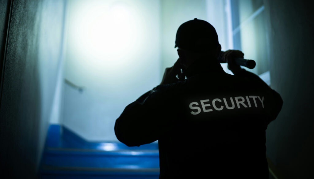 A security guard, seen from behind in silhoutte, with the word