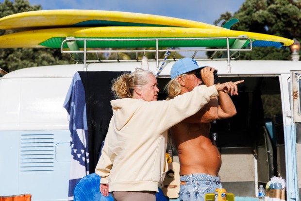 Shauna Aguirre, 60, and her brother Richard Aguirre, 58, try to spot the USS Murtha aiding the Artemis II crew after splashdown at Sunset Cliffs on Friday. (Kristian Carreon / The San Diego Union-Tribune)