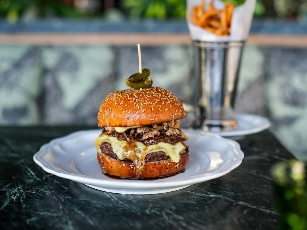 The French Onion Burger, served with pomme frites, at Trust Restaurant Group's À L'ouest, a modern French brasserie in North Park. (Trust Restaurant Group)