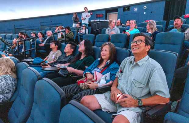 April 10, 2026_San Marcos, CA_Waiting for the start of the 7:00 p.m. show at the Palomar College Planetarium are Julian Chan and his wife Maria with their daughter Judy, her husband Peter and their son Edison, 12. They're watching a live broadcast of the astronauts exiting the Artemis 2 spacecraft after its splashdown. (No photos allowed during the show). (Charlie Neuman / For The San Diego Union-Tribune)