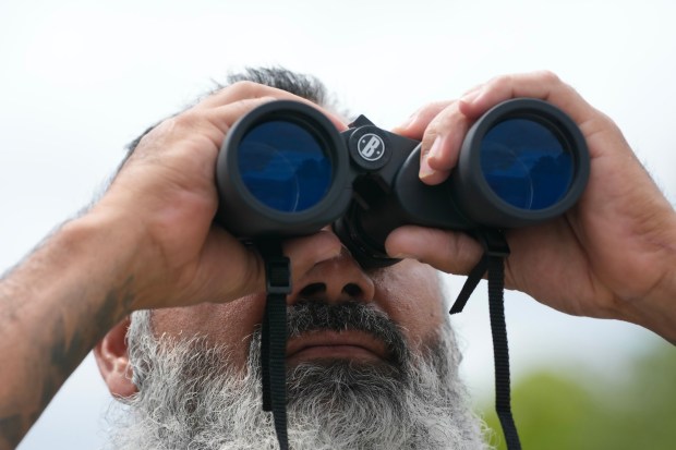 On Tuesday, March 31, 2026, in Poway, Jason Lavigne uses binoculars to monitor one of the three locations where artifacts have been discovered on the construction site for the Hidden Valley Ranch development. Lavigne is one of the tribal historic preservation officers for the San Pasqual Band of Mission Indians. (Nelvin C. Cepeda / The San Diego Union-Tribune)