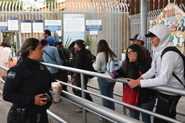 A Tijuana municipal police informs Viramontes Faeith (center), a prospective San Diego State University (SDSU) student, who was unaware about the new U.S. Customs and Border Protection app that allows San Diego higher education students living in Mexico to enter through an expedited lane at the San Ysidro Port of Entry in Tijuana on Thursday, April 23, 2026. To use the lane college students must download a CBP app to sign up to join the free Coordinated Access Program offered to students crossing the border. (Carlos Moreno / The San Diego Union-Tribune)