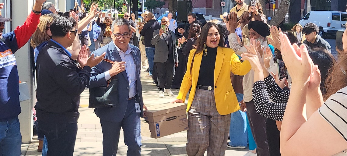 two people carrying a box between two lines of people