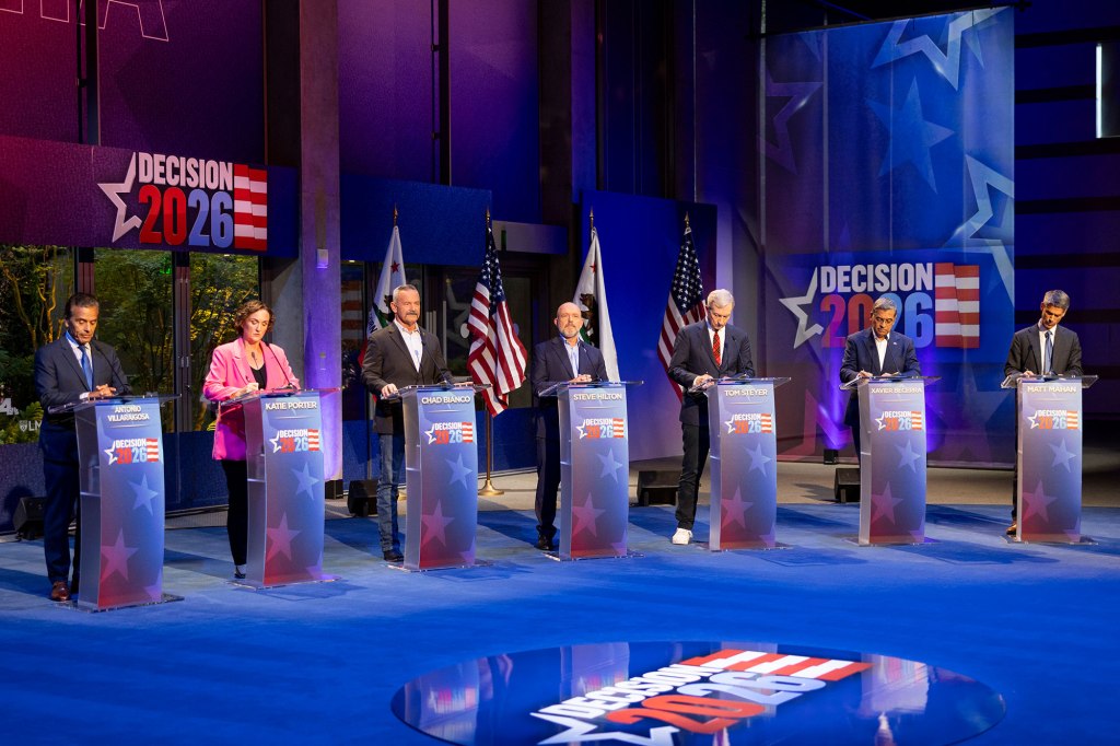 Seven candidates at podiums during a political debate for "Decision 2026."