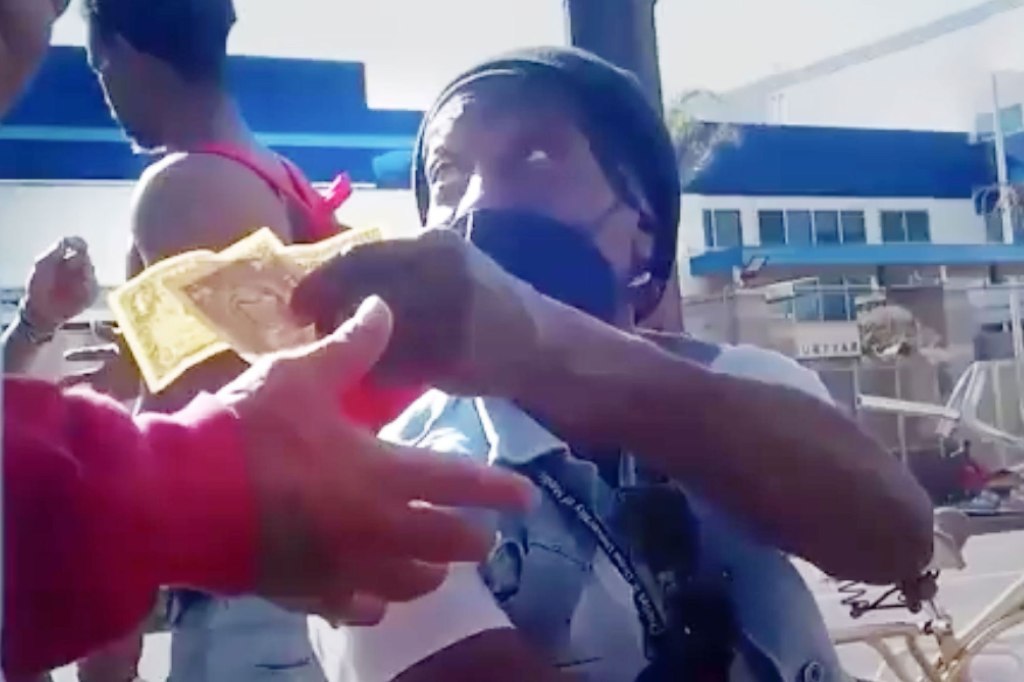A person in a black beanie and face mask receives money.